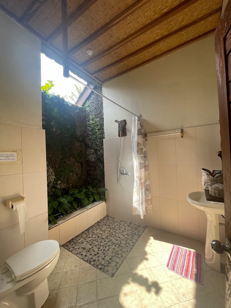 Bright open-air bathroom with bamboo ceiling and plants