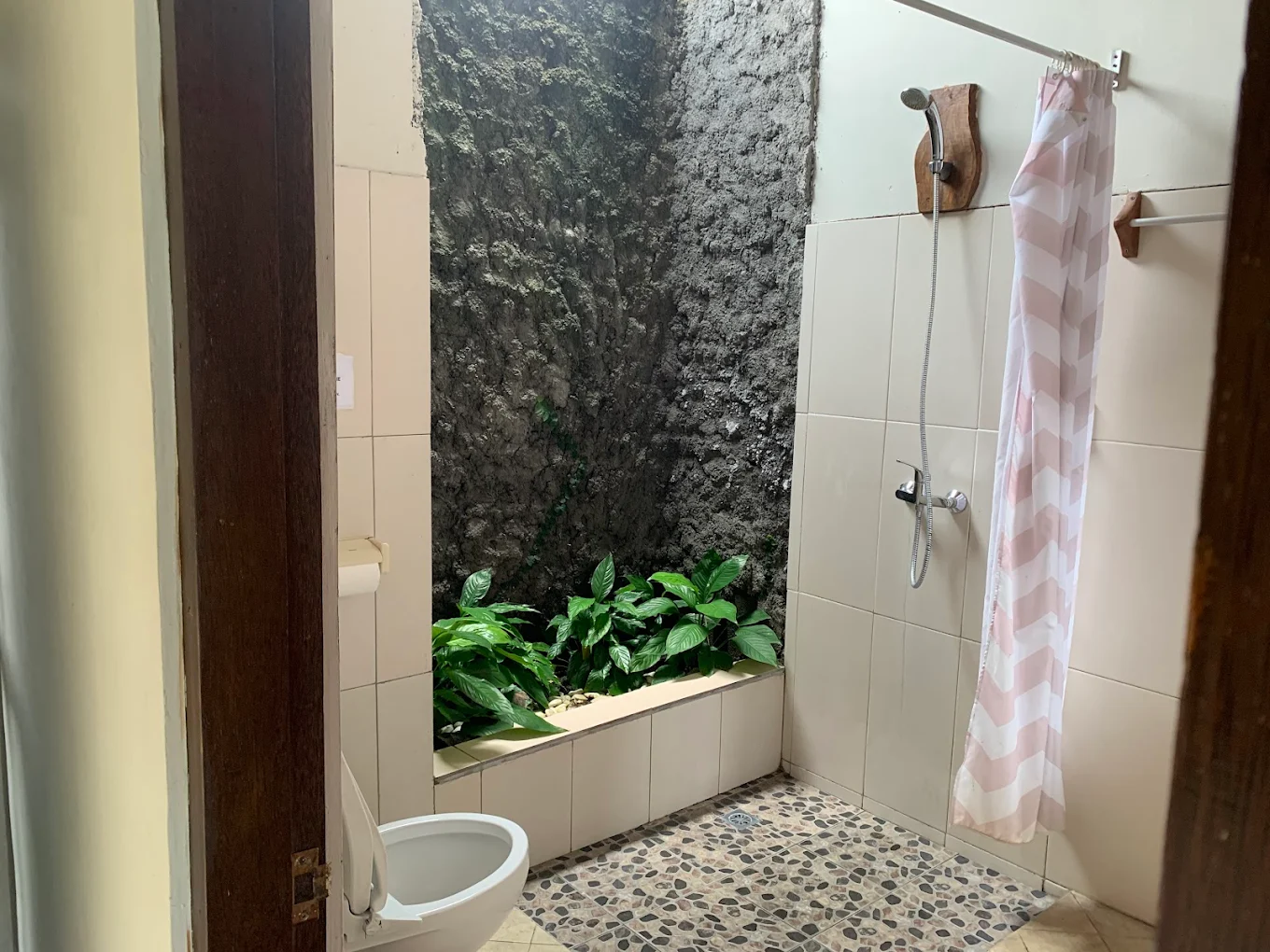 Open-air bathroom with a living green stone wall