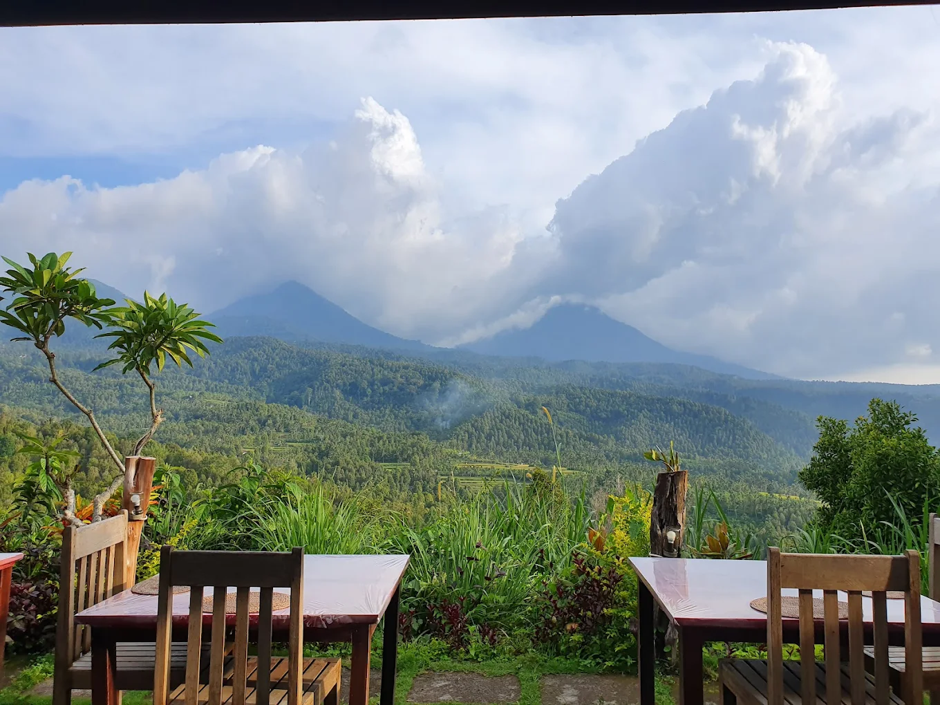Dining tables set before a cloudy volcano view