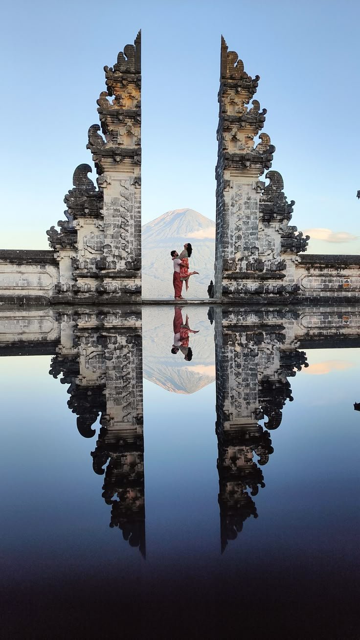 Couple at the Gates of Heaven temple with Mount Agung reflected in the water