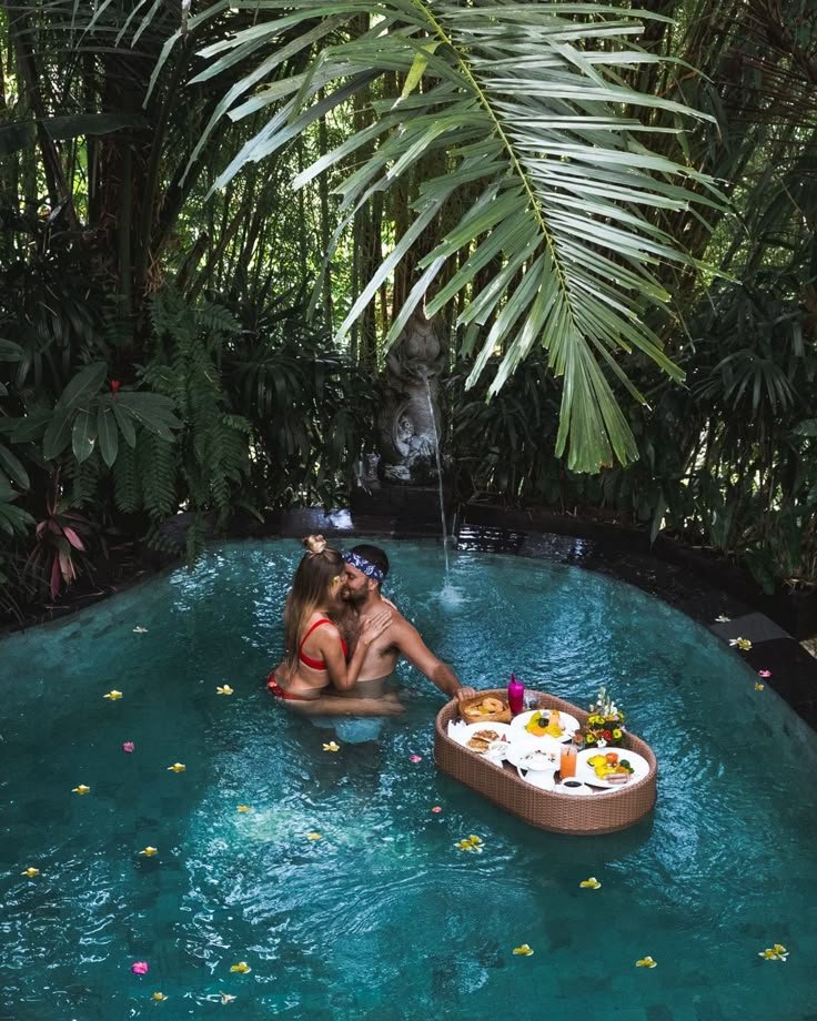 Couple embracing in a private jungle pool with a floating breakfast and flowers