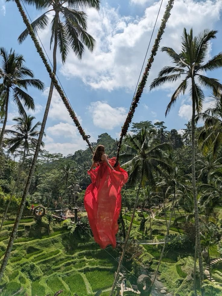 Woman in a flowing red dress on a jungle swing above the rice terraces